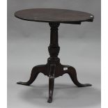 An 18th century oak tip-top wine table, the circular top raised on a turned column and tripod