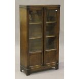 An early 20th century oak glazed bookcase, fitted with a pair of doors, raised on bracket feet,