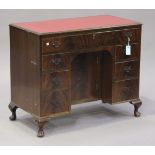 A 20th century reproduction walnut kneehole desk, fitted with drawers and a cupboard, on cabriole