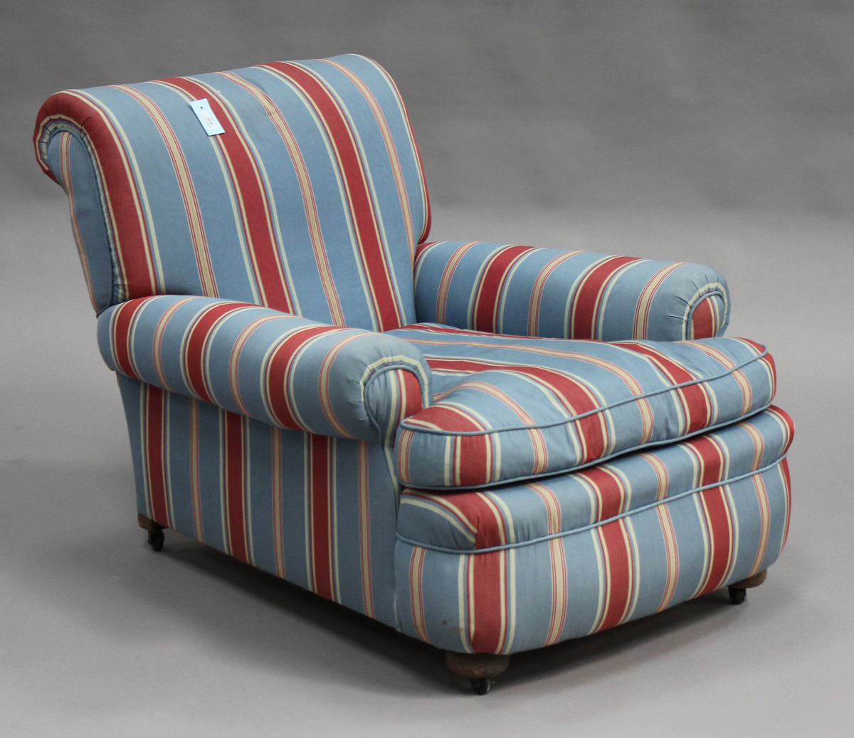 An early 20th century Howard & Sons style scroll armchair, upholstered in blue striped fabric, on