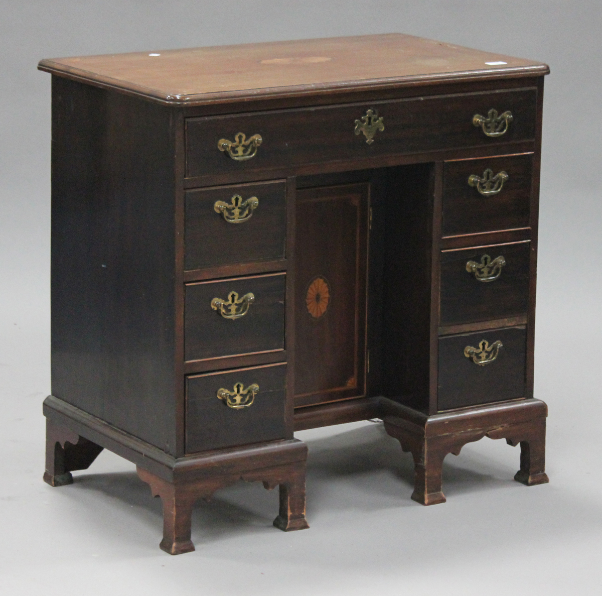 A 19th century mahogany kneehole desk, the moulded top inlaid with an oval fan patera above seven