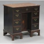 A 19th century mahogany kneehole desk, the moulded top inlaid with an oval fan patera above seven