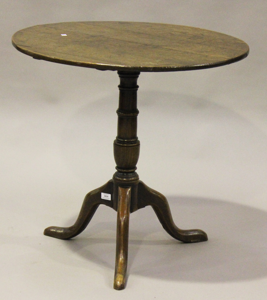 A George III provincial oak tip-top wine table, the circular top above a turned stem and tripod