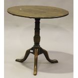 A George III provincial oak tip-top wine table, the circular top above a turned stem and tripod