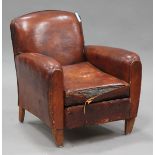 An early 20th century brown leather club armchair, raised on tapering legs, height 77cm, width