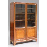 A George III satinwood glazed bookcase with ebony crossbanded borders and parcel gilding, fitted