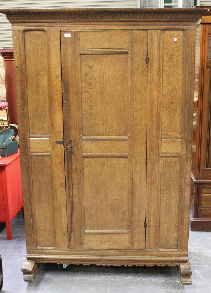 An 18th century Continental oak cupboard, the carved pediment above a single panelled door, on