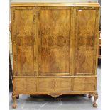 An Art Deco burr walnut side cabinet with carved decoration, fitted with three doors revealing
