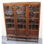 A George V oak bookcase-on-stand, the astragal glazed doors raised on block legs united by