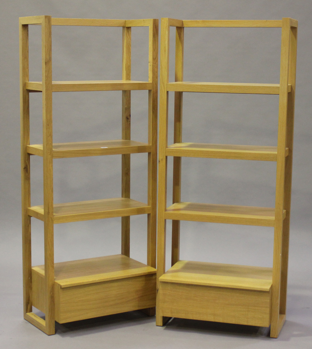 A pair of modern oak open bookcases, each fitted with a drawer, height 175cm, width 70cm.Buyer’s