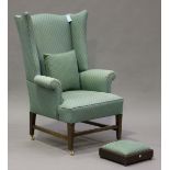 An early 20th century George III style wing back armchair, upholstered in green fabric, on square