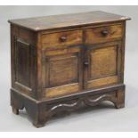 An 18th century oak side cupboard, possibly Welsh, fitted with two drawers above a pair of panel