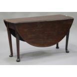 A George III mahogany circular drop-flap dining table, raised on turned tapering legs and pad