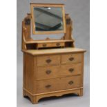 An Edwardian Art Nouveau oak dressing chest, the swing mirror above two short and two long