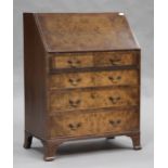 A 20th century reproduction walnut bureau, the fall front above two short and three long drawers, on