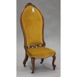 A late Victorian walnut showframe nursing chair with carved decoration, upholstered in golden