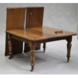 An Edwardian oak extending dining table with three extra leaves, raised on turned tapering legs