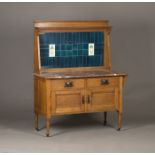 An Edwardian Arts and Crafts oak washstand, possibly by Liberty & Co, the shelf back inset with