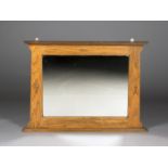 An early 20th century Arts and Crafts oak framed overmantel wall mirror with a flared pediment and