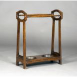 An Edwardian Arts and Crafts oak stick stand, the pierced end supports united by a platform base