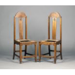 A pair of Edwardian Arts and Crafts oak side chairs, in the manner of M.H. Baillie Scott, the arched