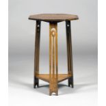 An Edwardian Arts and Crafts oak occasional table, the octagonal top and triangular undertier with