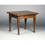 An early 20th century Arts and Crafts oak drawleaf dining table, the frieze with a carved band,