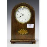 An Edwardian stained beech mantel timepiece, the white enamel dial with black Arabic numerals, the