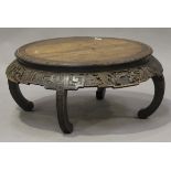 An early 20th century Chinese elm circular occasional table, the shaped apron carved with figures