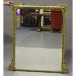 A late Victorian gilt composition overmantel mirror, the shaped frame decorated with bands of