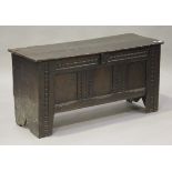 A 17th century oak coffer, the hinged lid above a triple panel front with carved ropetwist