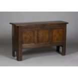A 17th century oak panel fronted coffer, the single piece plank top above a stop fluted frieze and