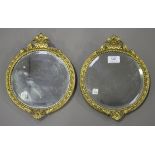 A pair of small late 19th century gilt composition circular wall mirrors with bevelled plate glass