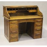 A George V oak roll-top desk, the tambour front revealing pigeonholes and drawers above seven