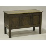 An 18th century oak coffer, the hinged lid above a panelled front carved with lunettes and