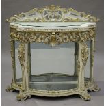 A mid-19th century and later Rococo Revival white painted and gilded serpentine fronted display