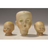 Two German bisque baby dolls' heads with painted features, together with another doll's head,