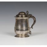 A George II silver tankard, the domed hinged lid and scroll thumbpiece above a girdled low bellied