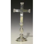 A George V silver altar cross, raised on a baluster stem and circular foot, decorated in relief with