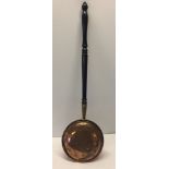 A brass warming pan with black wood handle.