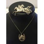 A silver pendant in the form of a horseshoe and a horses head on a white metal chain, together