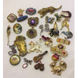 A tub with a good quantity of costume jewellery brooches to include a cat set with purple stones