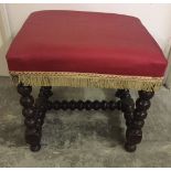 A large square bobbin leg stool with red upholstery.