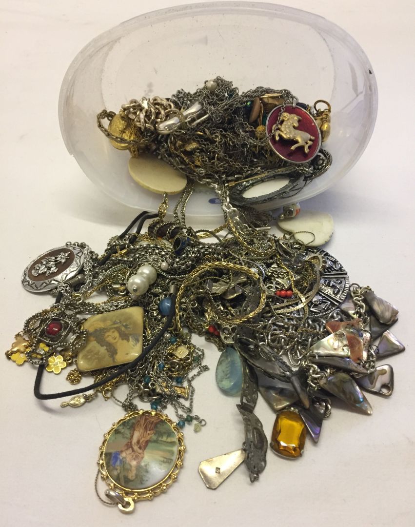 A tub containing a large quantity of costume jewellery chains and pendants.