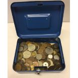 A blue money tin containing world coins.