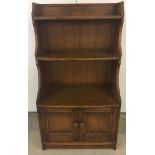 A small Ercol waterfall book case with 2 door cupboard. Base 110cm high.