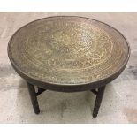 A small fold up brass top table with wooden base.