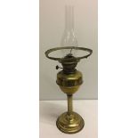 A large brass oil lamp with fluted stem and glass chimney (shade missing).