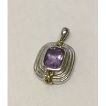 A white & yellow 9ct gold pendant set with a central amethyst.