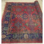 A large Persian rug of dark red, blue, green colouration. Thread bare in areas. Approx 210 x 300cm.
